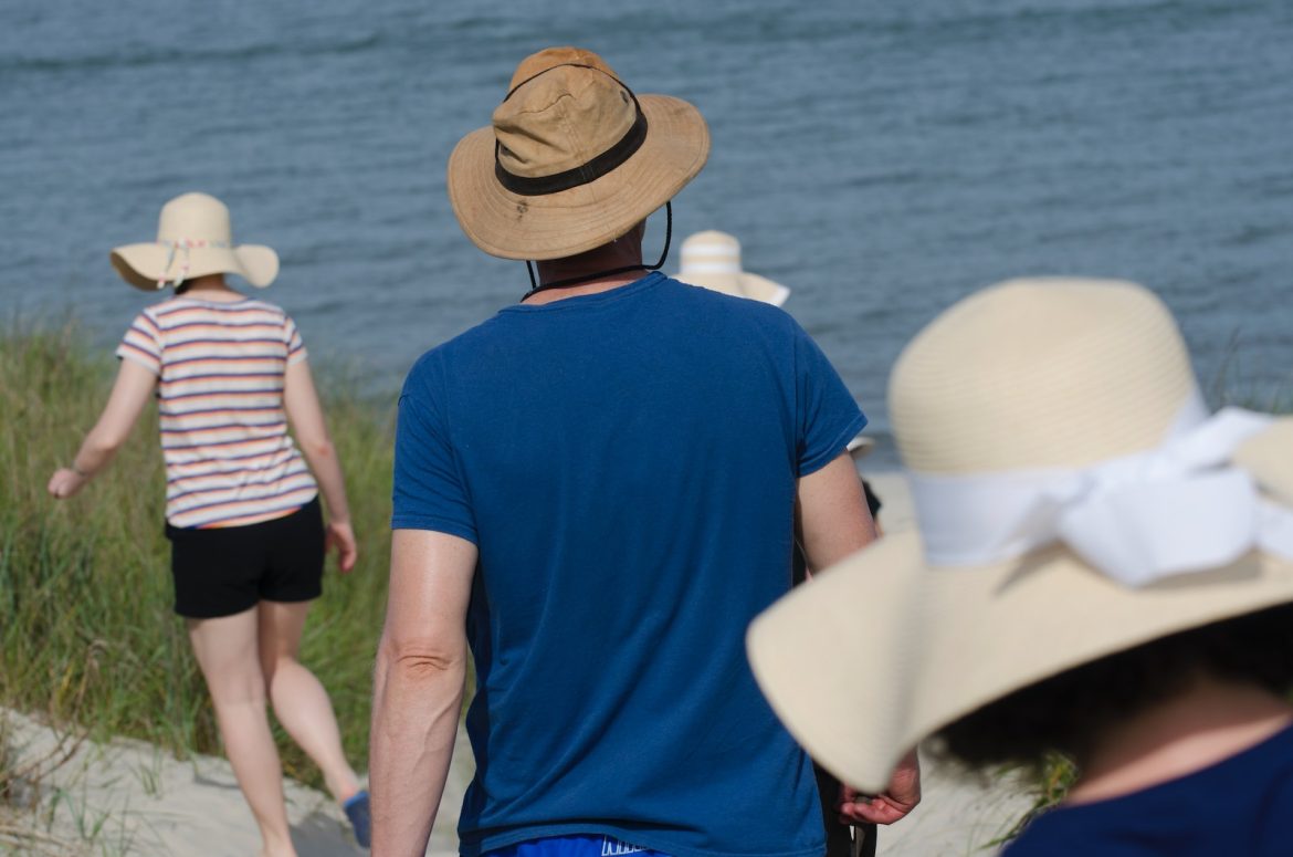 man in blue crew neck t-shirt wearing brown fedora hat standing beside woman in white